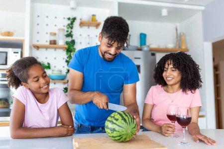 Téléchargez les photos : Famille de trois enfants. Joyeux jeune famille profitant d'une pastèque. Famille manger une tranche de pastèque et rire ensemble. - en image libre de droit