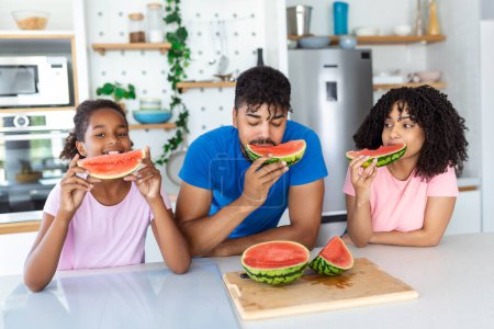 Photo for Family eats a sweet watermelon in the kitchen. A man and a woman with daughter eat a ripe watermelon in the kitchen. Happy family eating watermelon. - Royalty Free Image