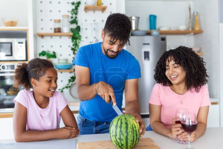 Photo for Family of three. Happy young family enjoying a watermelon. Family eating a watermelon slice and laughing together. - Royalty Free Image