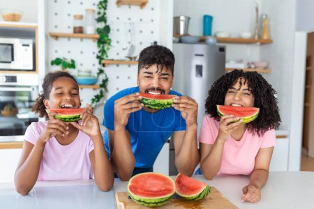 Photo for Healthy food at home. Happy family in the kitchen. Mother, father and child daughter eating watermelon slices - Royalty Free Image