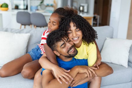 Téléchargez les photos : Happy joyeuse famille papa, maman et fille s'amuser câlins sur le canapé à la maison. - en image libre de droit
