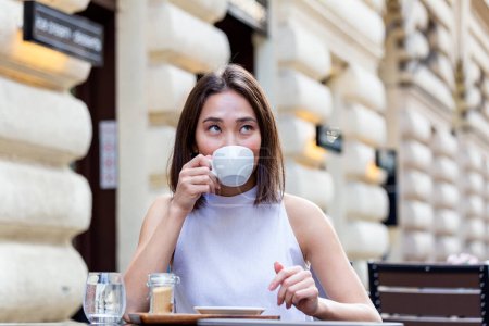Téléchargez les photos : Belle jeune femme asiatique avec une tasse de café. Femme aime le café frais le matin avec lever de soleil au café Belle femme buvant du café le matin assis à l'extérieur - en image libre de droit