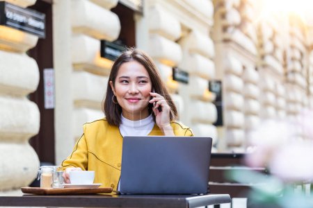 Photo for Asian Woman working on laptop at a cafe. Young woman working on a laptop. Beautiful young woman working with laptop from coffee shop. Attractive woman sitting in a cafe with a laptop - Royalty Free Image