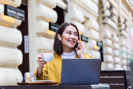Téléchargez les photos : Femme asiatique travaillant sur un ordinateur portable dans un café. Une jeune femme qui travaille sur un ordinateur portable. Belle jeune femme qui travaille avec un ordinateur portable du café. Belle femme assise dans un café avec un ordinateur portable - en image libre de droit
