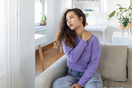 Photo for Asian woman suffering from backache at home. Lower Back Pain . Woman feels back pain massaging aching muscles, sad woman suffers from low-back - Royalty Free Image