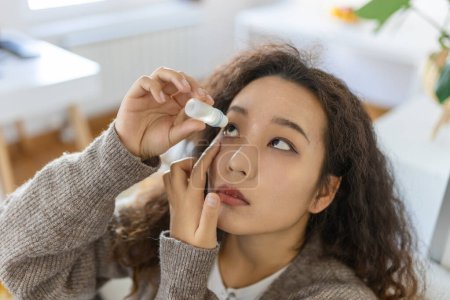 Téléchargez les photos : Asian Woman using eye drop, woman dropping eye lubricant to treat dry eye or allergy, sick woman treating eyeball irritation or inflammation woman suffering from irritated eye, optical symptoms - en image libre de droit