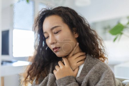 Téléchargez les photos : Sick day at home. Young Asian woman has sore throat and common cold. Cough. Closeup Of Beautiful Young Woman Caught Cold Or Flu Illness. Portrait Of Unhealthy Girl with coronavirus, covid19 symptoms - en image libre de droit