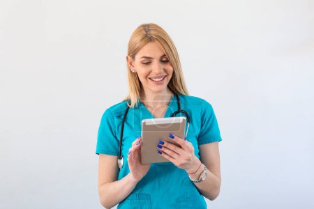 Foto de Mujer joven médico clínico en matorrales utilizando touchpad mientras se comunica con los pacientes en línea - Imagen libre de derechos