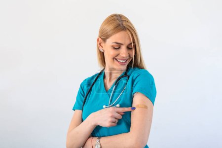 Foto de Young woman doctor with adhesive bandage on her arm after Coronavirus vaccine. First aid. Medical, pharmacy and healthcare concept. - Imagen libre de derechos