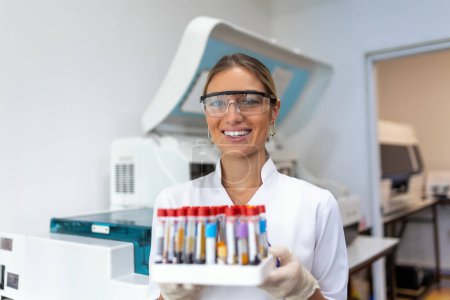 Photo for Blood test tubes. Female scientist examining blood test tubes at her laboratory dna testing analysis profession specialist clinician experienced medicine healthcare doctor - Royalty Free Image