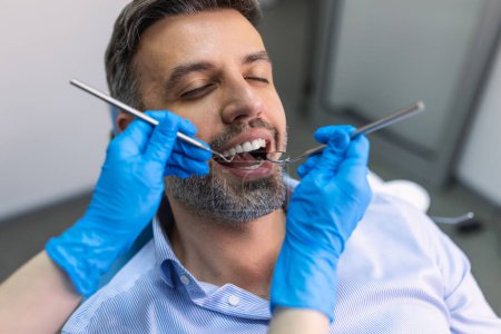 Téléchargez les photos : Un sourire incroyable ! Vue du dessus du dentiste examinant sa patiente dans le cabinet du dentiste - en image libre de droit
