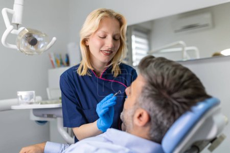 Téléchargez les photos : Dentiste femme guérissant la cavité dentaire dans des gants bleus. Dentiste caries traitement au cabinet de la clinique dentaire. Personnes, médecine, stomatologie et concept de soins de santé - en image libre de droit