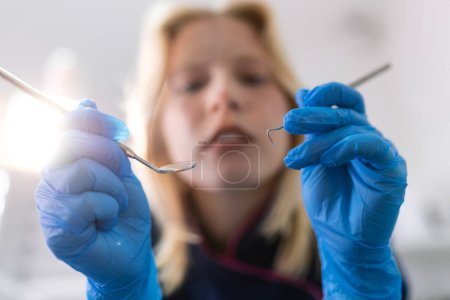 Photo for Close up, patients view of a dentist. Beautiful dentist in surgical gloves is holding tools and looking at camera - Royalty Free Image