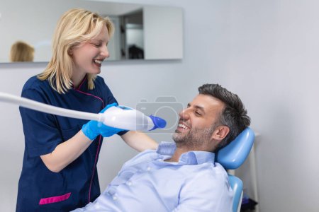 Téléchargez les photos : Vue rapprochée de l'homme subissant un traitement de blanchiment des dents au laser pour éliminer les taches et la décoloration. Blanchiment des dents à la clinique dentaire. - en image libre de droit