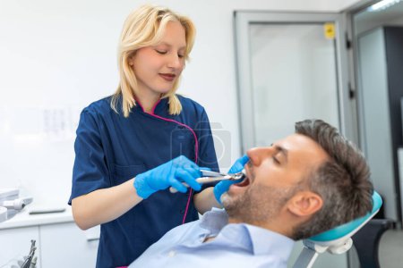 Téléchargez les photos : Chirurgien enlevant la dent. Dentiste utilisant une pince chirurgicale pour enlever une dent en clinique - en image libre de droit
