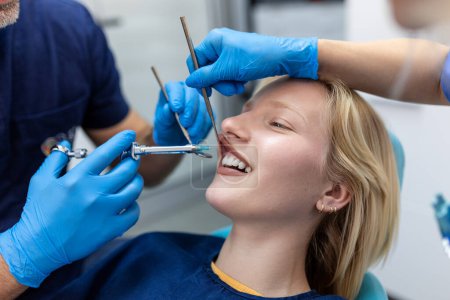 Photo for Painkiller anesthesia injection. Dentist examining a patient's teeth in modern dentistry office. Closeup cropped picture with copyspace. Doctor in disposable medical facial mask. - Royalty Free Image