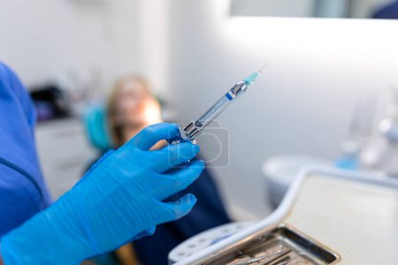 Photo for Close up of anesthesia syringe in the hands of a dentist doctor. Anesthetist dentist doctor holds in his hand anesthesia syringe prior to dental surgery. Hand in a rubber glove - Royalty Free Image
