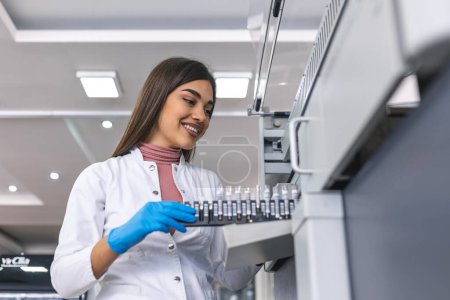 Photo for Close-up Female Research Scientist Takes Test Tube with Blood Sample before Putting them Into Medical Analyzing Equipment. Scientist Works in Modern Pharmaceutical Laboratory - Royalty Free Image