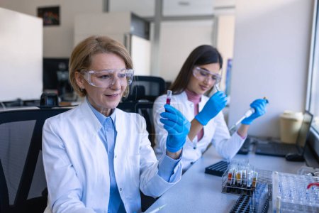 Foto de Female Research Scientist utiliza micro pipeta mientras trabaja con tubos de ensayo. Personas en Laboratorio Farmacéutico Innovador con Equipo Médico Moderno para Investigación Genética. - Imagen libre de derechos