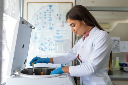 Téléchargez les photos : Technicien chargeant un échantillon sur une centrifugeuse dans le laboratoire médical ou scientifique - en image libre de droit
