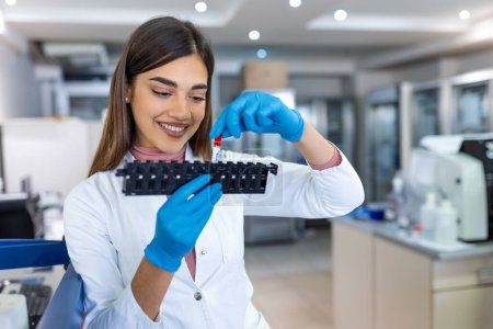 Photo for Laboratory assistant putting test tubes into the holder. Scientist doctor looking at blood test tube working at biochemistry experiment in microbiology hospital laboratory. - Royalty Free Image