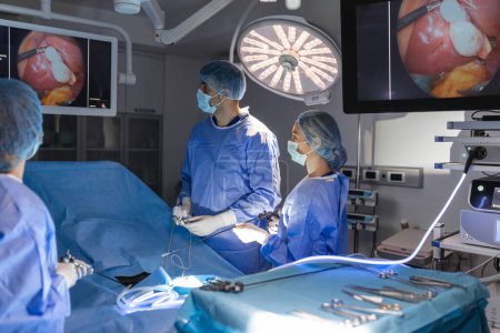 Téléchargez les photos : Processus d'opération de chirurgie gynécologique à l'aide d'un équipement laparoscopique. Groupe de chirurgiens en salle d'opération avec équipement chirurgical. Contexte - en image libre de droit