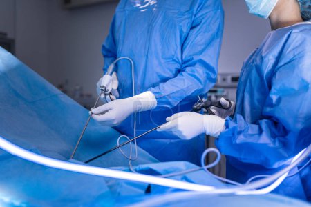 Téléchargez les photos : Trois chirurgiens en chirurgie laparoscopique. Les médecins regardent l'image sur le moniteur. Médecine et concept de santé. Organe interne du patient vu sur écran d'ordinateur - en image libre de droit