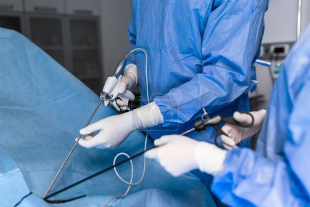 Téléchargez les photos : Le chirurgien enfonce l'instrument dans l'abdomen du patient. Le chirurgien fait une opération laparoscopique dans la salle d'opération. Chirurgie mini-invasive. - en image libre de droit