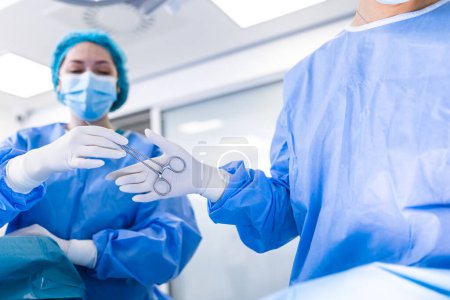 Photo for Low Angle Shot in the Operating Room, Assistant Hands out Instruments to Surgeons During Operation. Surgeons Perform Operation. Professional Medical Doctors Performing Surgery. - Royalty Free Image