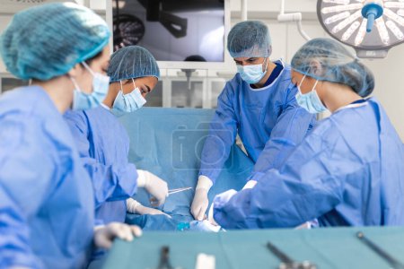 Photo for Surgeons doing surgery in operating theatre. Male and female surgeons operating patient. Medical professionals are wearing scrubs. - Royalty Free Image