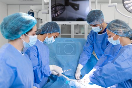 Foto de Medical team performing operation. Group of surgeon at work in operating theatre toned in blue. Doctor operation in operation room at hospital concept for insurance advertising. - Imagen libre de derechos