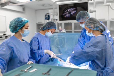 Photo for Surgeons doing surgery in operating theatre. Male and female surgeons operating patient. Medical professionals are wearing scrubs. - Royalty Free Image