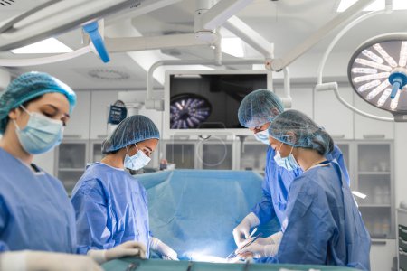 Photo for Surgery operation. Group of surgeons in operating room with surgery equipment. Medical background, selective focus. Surgeon team working together while operation - Royalty Free Image