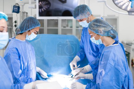 Photo for Team of Professional surgeon, Assistants and Nurses Performing Invasive Surgery on a Patient in the Hospital Operating Room. Surgeons Talk and Use Instruments. Real Modern Hospital. - Royalty Free Image
