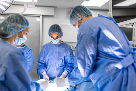 Foto de Group of medical team urgently doing surgical operation and helping patient in theater at hospital. Medical team performing surgical operation in a bright modern operating room - Imagen libre de derechos