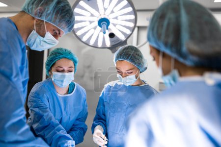 Foto de El equipo de cirujanos uniformados realiza una operación a un paciente en una clínica de cirugía cardíaca. Medicina moderna, un equipo profesional de cirujanos, salud. - Imagen libre de derechos