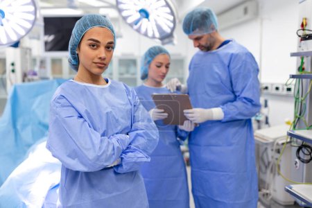 Photo for Portrait of female woman nurse surgeon OR staff member dressed in surgical scrubs gown mask and hair net in hospital operating room theater making eye contact smiling pleased happy looking at camera - Royalty Free Image