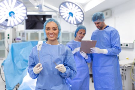 Téléchargez les photos : Portrait of happy woman surgeon standing in operating room, ready to work on a patient. Female medical worker in surgical uniform in operation theater. - en image libre de droit