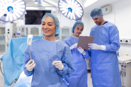Téléchargez les photos : Portrait of happy woman surgeon standing in operating room, ready to work on a patient. Female medical worker in surgical uniform in operation theater. - en image libre de droit