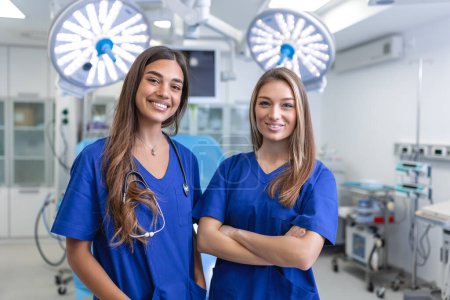 Photo for Young female medical professionals standing together. concept of health protection. Successful team of medical doctors are looking at camera and smiling while standing in hospital - Royalty Free Image