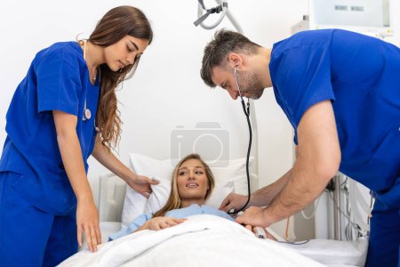 Photo for Hospital Ward: Friendly Doctor and nurse taking care of Beautiful Caucasian Female Patient Resting in Bed. Physician explains Test Results. Woman Recovering after Successful Surgery - Royalty Free Image