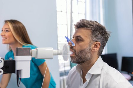 Foto de Hombre realizando prueba de función pulmonar y espirometría usando espirómetro en clínica médica. Espirrometría de los pulmones - Imagen libre de derechos