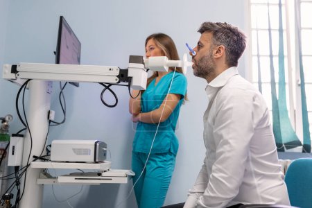 Téléchargez les photos : Homme effectuant un test de fonction pulmonaire et une spirométrie à l'aide d'un spiromètre à la clinique médicale. Spirométrie des poumons - en image libre de droit