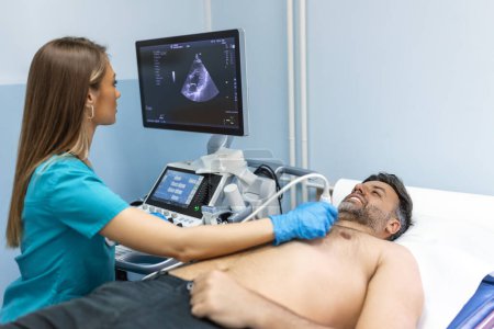 Ultraschalluntersuchung des Herzens durch Ärztin mit lächelnder Patientin.