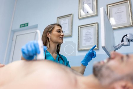 Téléchargez les photos : Examen par échographie cardiaque effectué par une femme médecin avec un patient souriant. - en image libre de droit