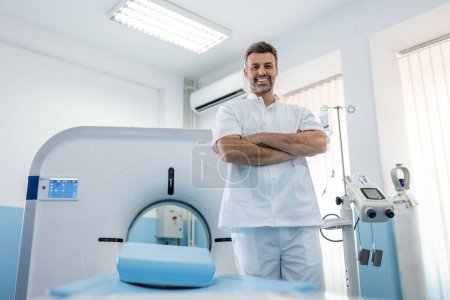 Photo for Confident male doctor oncology in magnetic resonance imaging or computed tomography room of a modern hospital. - Royalty Free Image