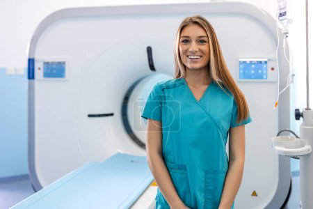 Foto de Hermosa mujer feliz médico radiólogo de pie en la sala de exploración CT CAT en el hospital. - Imagen libre de derechos