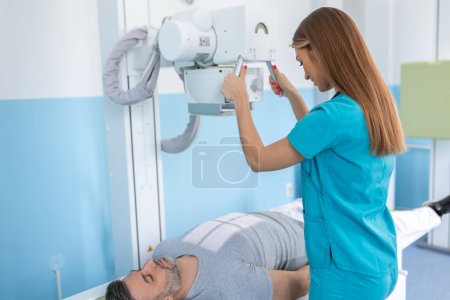 Female doctor sets up the machine to x-ray over patient. Radiologist and patient in a x-ray room. Classic ceiling-mounted x-ray system. Medical equipment