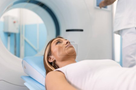 Téléchargez les photos : Patiente allongée sur un lit de balayage CT ou PET ou IRM, se déplaçant à l'intérieur de la machine pendant qu'elle analyse son cerveau et ses paramètres vitaux. - en image libre de droit