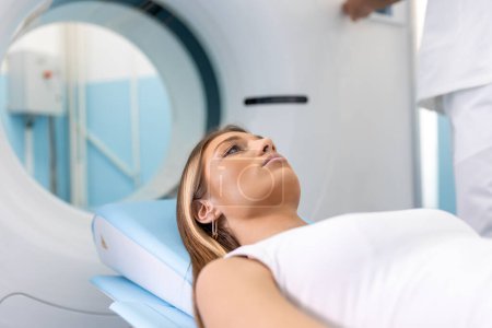 Téléchargez les photos : Patiente allongée sur un lit de balayage CT ou PET ou IRM, se déplaçant à l'intérieur de la machine pendant qu'elle analyse son cerveau et ses paramètres vitaux. - en image libre de droit